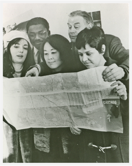 a black and white photo of many people looking at one map